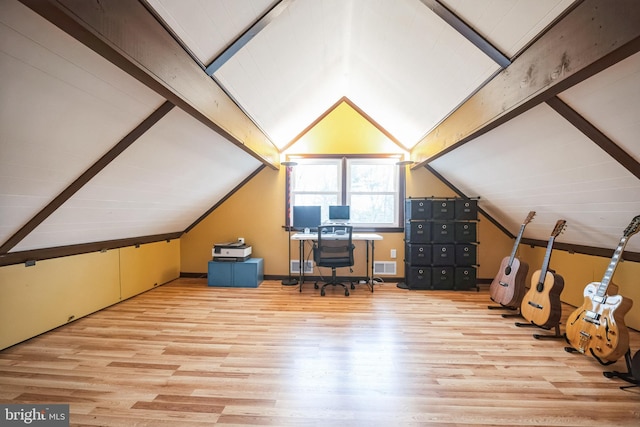 unfurnished office with light wood-type flooring and lofted ceiling with beams