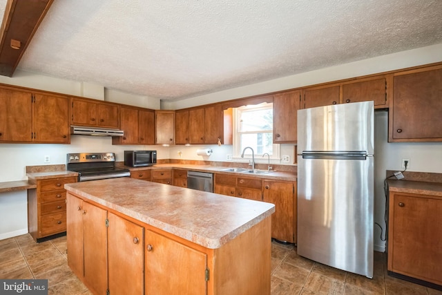 kitchen with a textured ceiling, a center island, sink, and appliances with stainless steel finishes