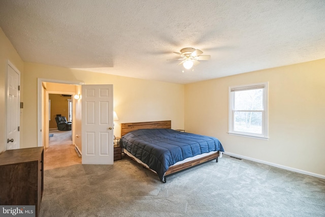 carpeted bedroom featuring ceiling fan and a textured ceiling