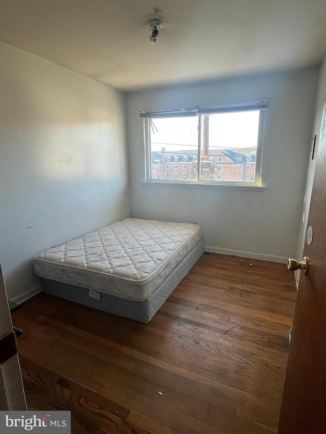 bedroom with multiple windows and dark wood-type flooring