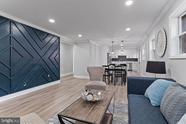 living room featuring sink, crown molding, and light hardwood / wood-style flooring