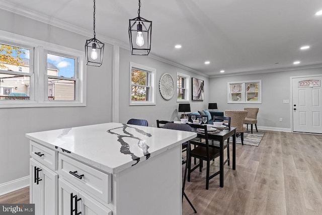 kitchen with pendant lighting, white cabinets, light wood-type flooring, a kitchen island, and a breakfast bar area