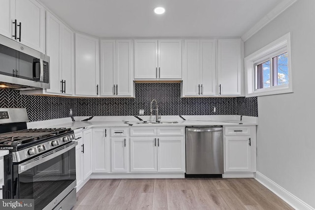 kitchen with sink, white cabinets, light hardwood / wood-style flooring, and appliances with stainless steel finishes