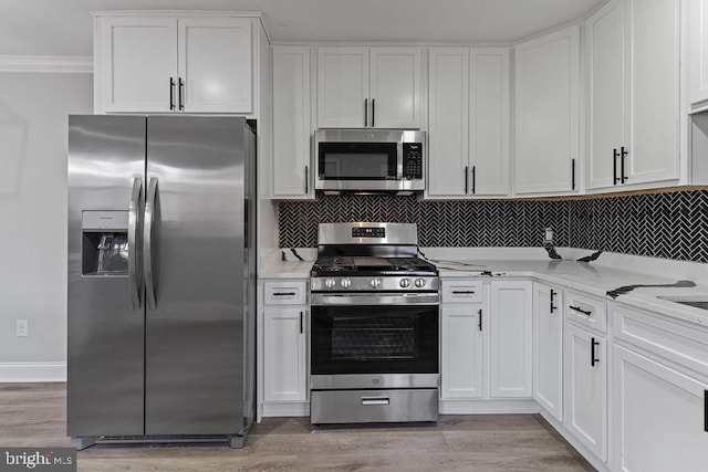 kitchen with light wood-type flooring, tasteful backsplash, ornamental molding, stainless steel appliances, and white cabinets