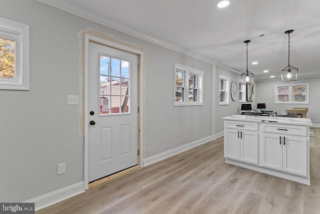 kitchen featuring white cabinetry, ornamental molding, hanging light fixtures, and light hardwood / wood-style floors