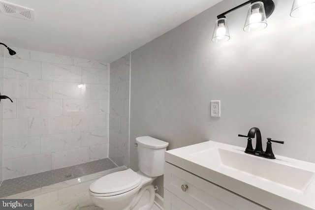 bathroom with a tile shower, vanity, and toilet