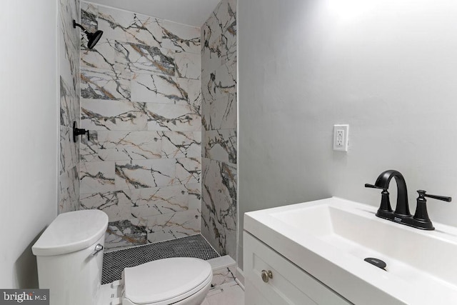 bathroom with toilet, a tile shower, and vanity