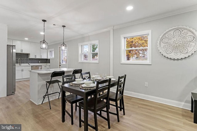 dining area with sink, light hardwood / wood-style flooring, and ornamental molding