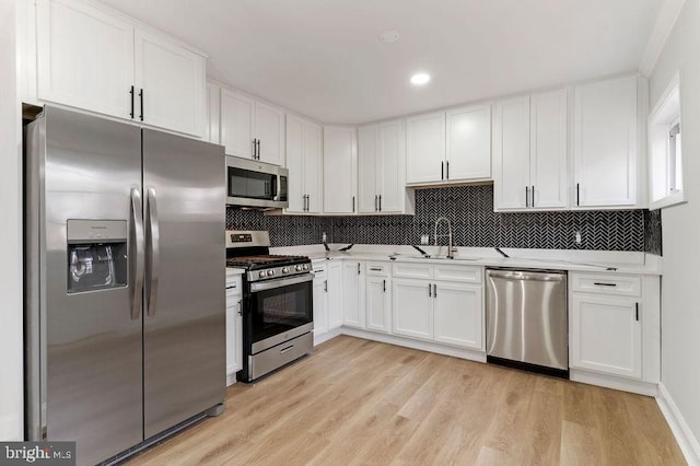 kitchen featuring white cabinetry, sink, tasteful backsplash, light hardwood / wood-style flooring, and appliances with stainless steel finishes