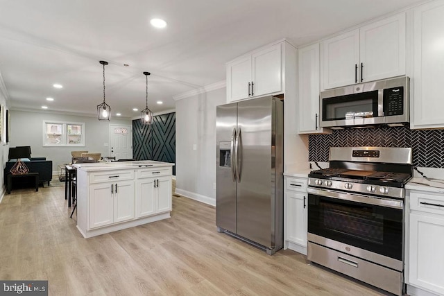 kitchen featuring light wood-type flooring, ornamental molding, stainless steel appliances, decorative light fixtures, and white cabinetry