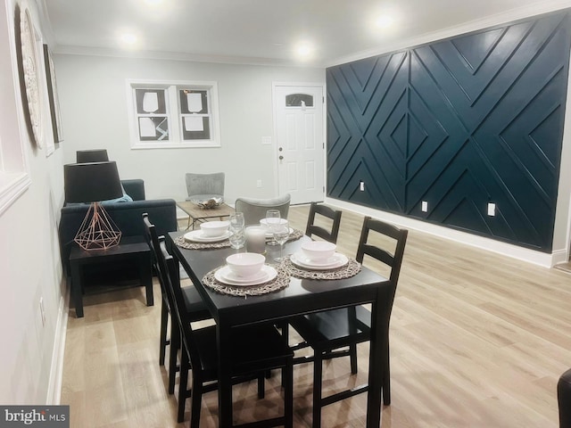 dining room with light wood-type flooring and crown molding