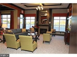 carpeted living room with ornamental molding, a healthy amount of sunlight, and a notable chandelier