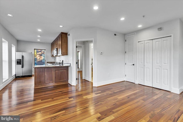 kitchen featuring stainless steel appliances, light stone countertops, and dark hardwood / wood-style flooring