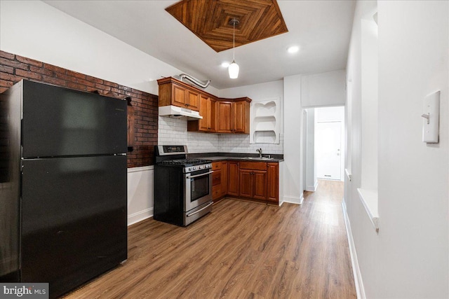 kitchen with black fridge, sink, gas range, decorative backsplash, and wood-type flooring