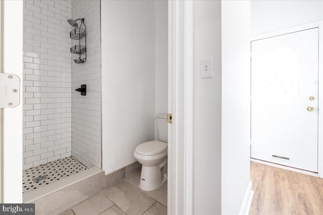 bathroom with tiled shower, hardwood / wood-style floors, and toilet