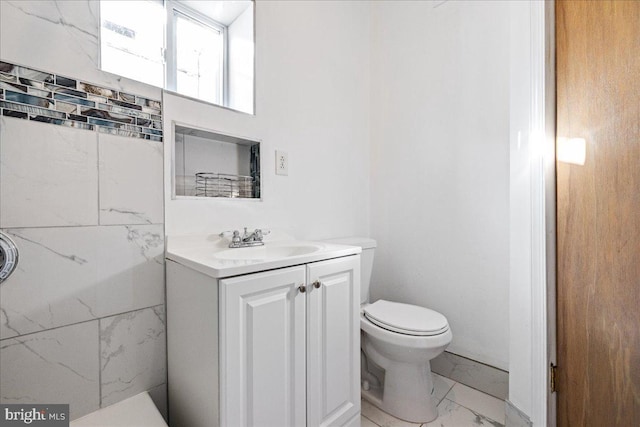 bathroom with vanity, tile walls, and toilet