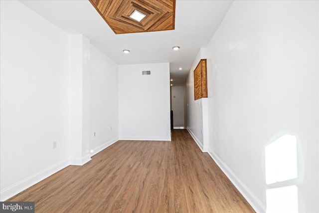 hallway featuring hardwood / wood-style flooring and a skylight