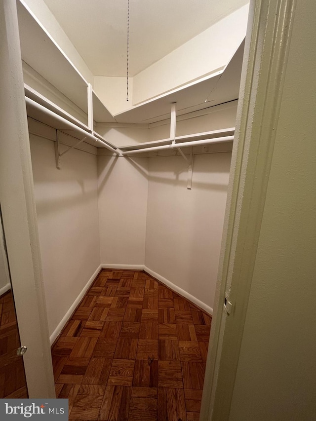 walk in closet featuring dark parquet flooring