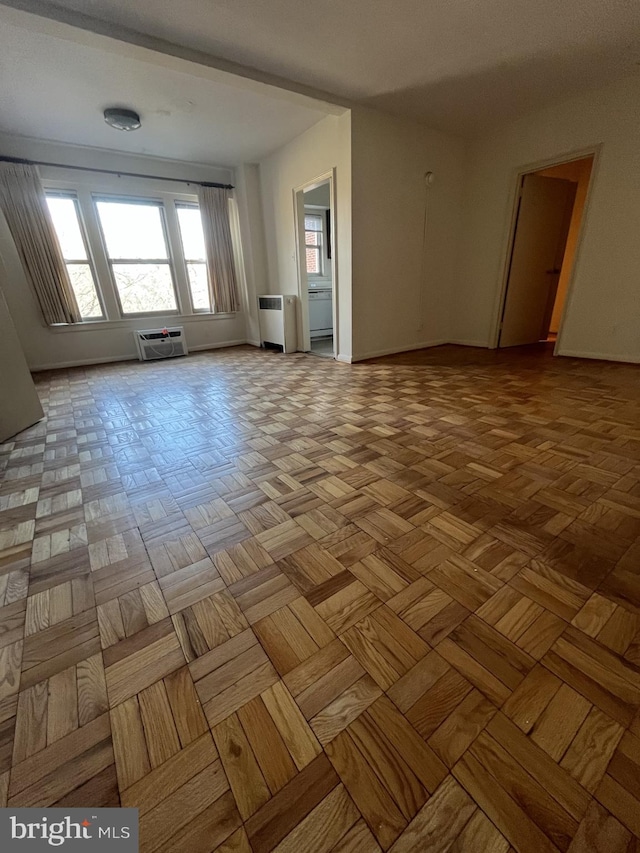 empty room with radiator, light parquet flooring, and a wall mounted air conditioner