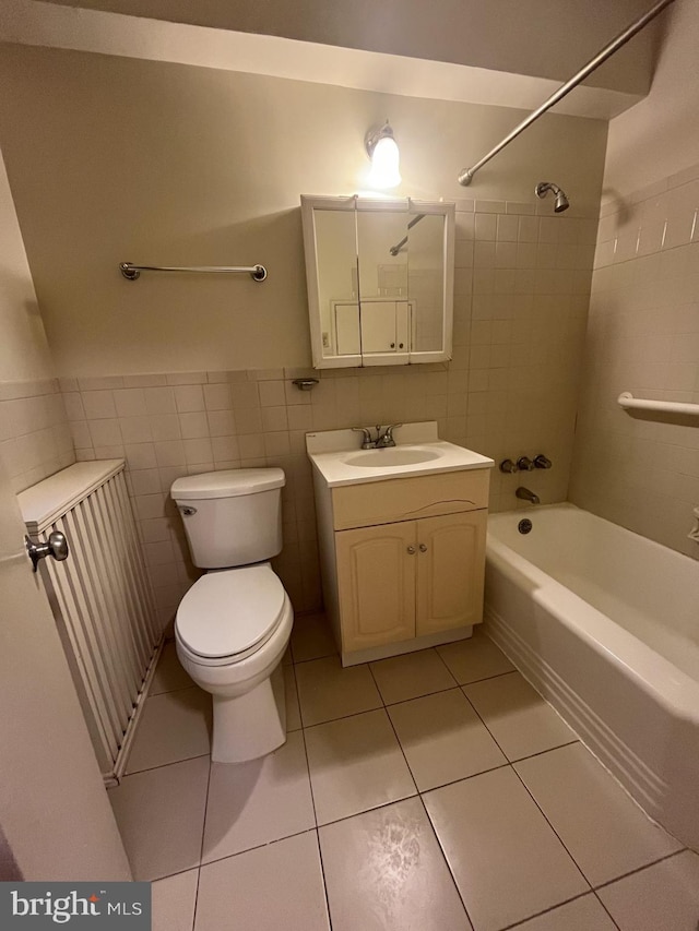 full bathroom featuring tile patterned flooring, toilet, vanity, tile walls, and tiled shower / bath