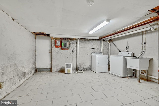 basement featuring electric panel, washer and clothes dryer, and sink