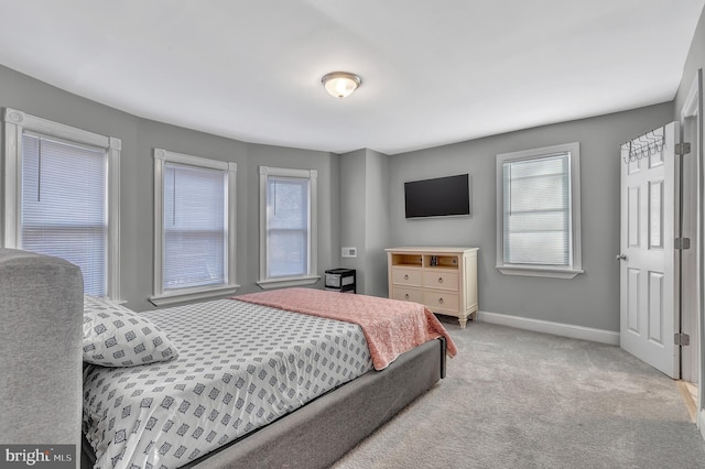 bedroom with multiple windows and light carpet