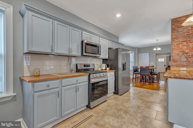 kitchen featuring gray cabinetry, a healthy amount of sunlight, hanging light fixtures, and appliances with stainless steel finishes