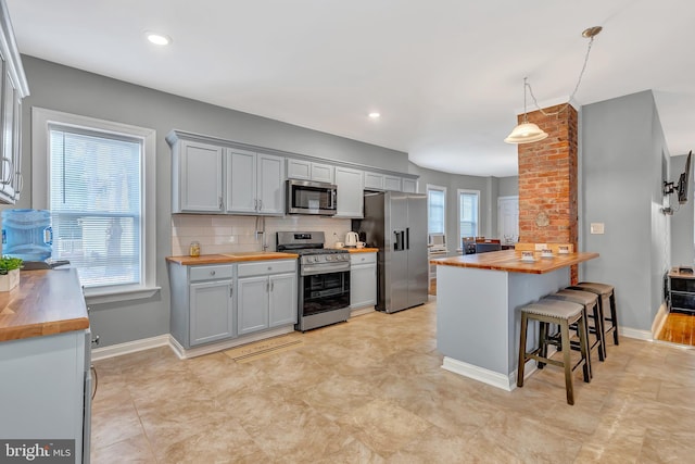 kitchen with a healthy amount of sunlight, stainless steel appliances, a breakfast bar area, and wooden counters