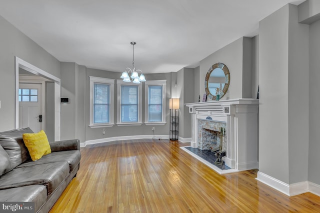 living room with hardwood / wood-style floors, a high end fireplace, and a chandelier