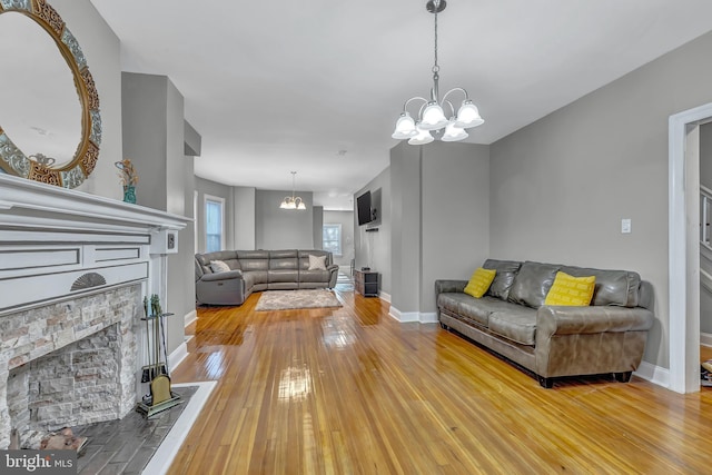 living room with hardwood / wood-style flooring, a notable chandelier, and a fireplace