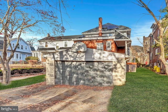 exterior space with a lawn, an outbuilding, a garage, and solar panels