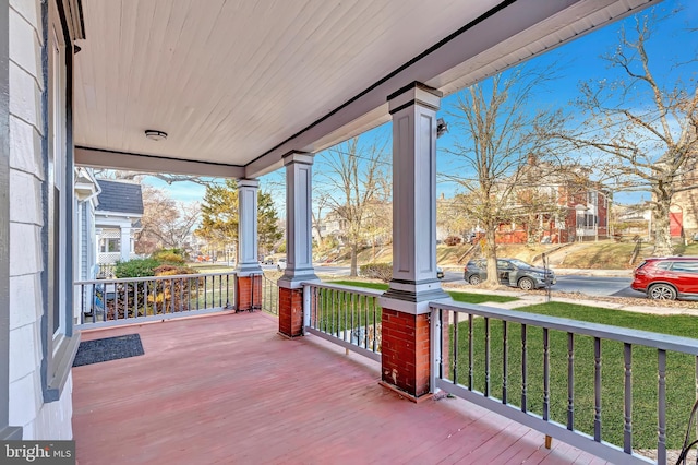 wooden deck featuring a porch and a yard