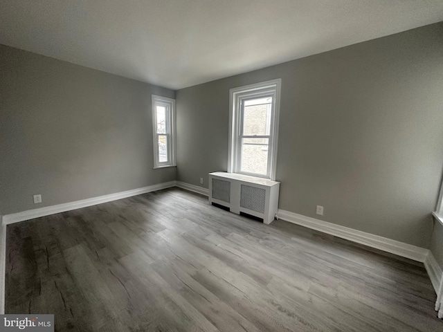 unfurnished room with radiator heating unit and light wood-type flooring