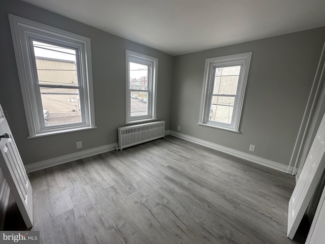 unfurnished room featuring light hardwood / wood-style floors and radiator heating unit