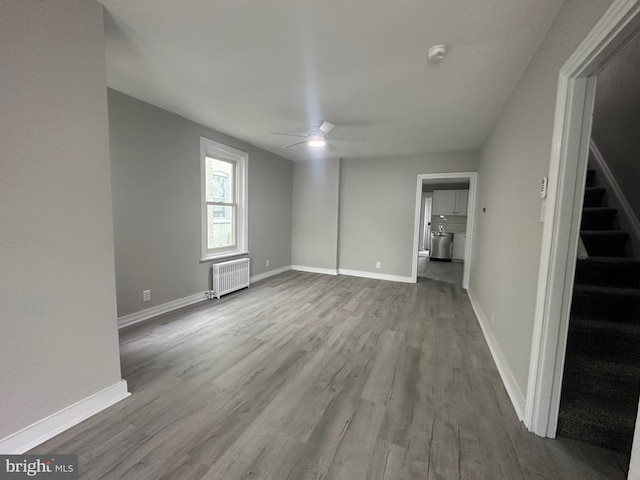 unfurnished room with light hardwood / wood-style floors, radiator, and ceiling fan