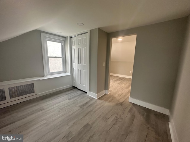 bonus room featuring radiator, lofted ceiling, and light wood-type flooring