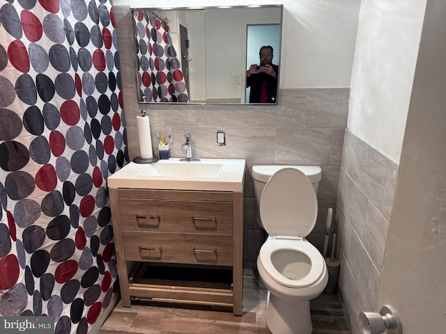 bathroom with vanity, toilet, and tile walls