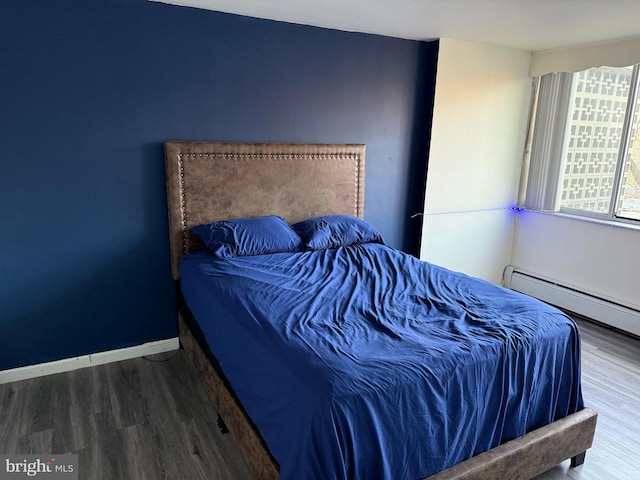 bedroom featuring hardwood / wood-style floors and a baseboard heating unit