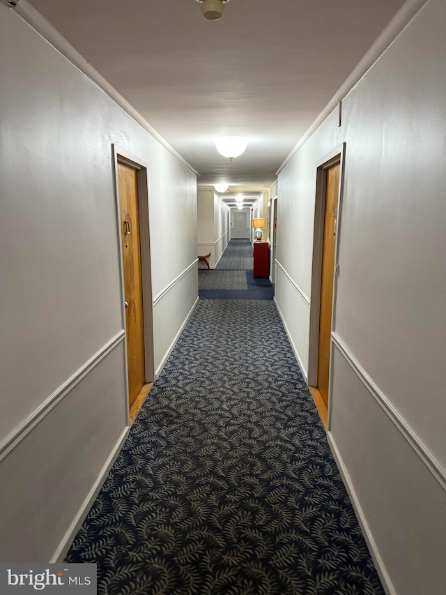 hallway featuring dark colored carpet and crown molding