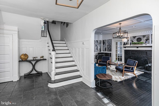 stairway with a chandelier and a brick fireplace