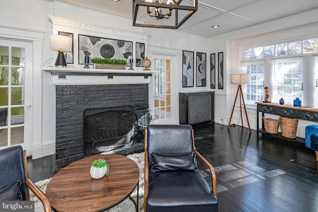 sitting room with dark hardwood / wood-style flooring, an inviting chandelier, and a brick fireplace