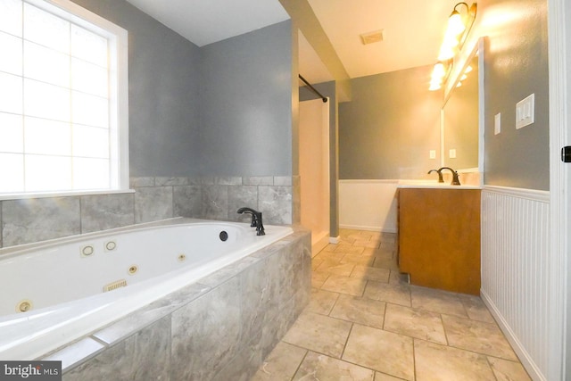 bathroom featuring tiled bath and vanity