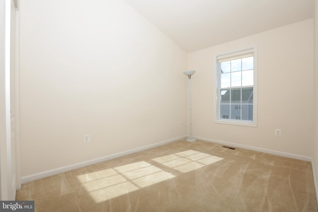 carpeted empty room featuring lofted ceiling