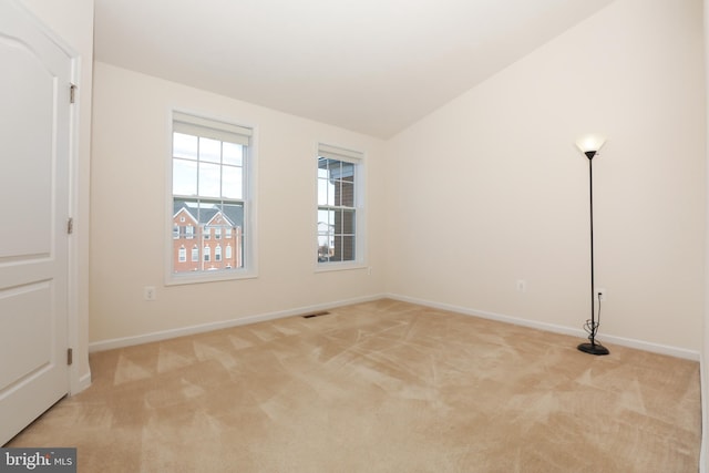 spare room featuring light carpet and lofted ceiling