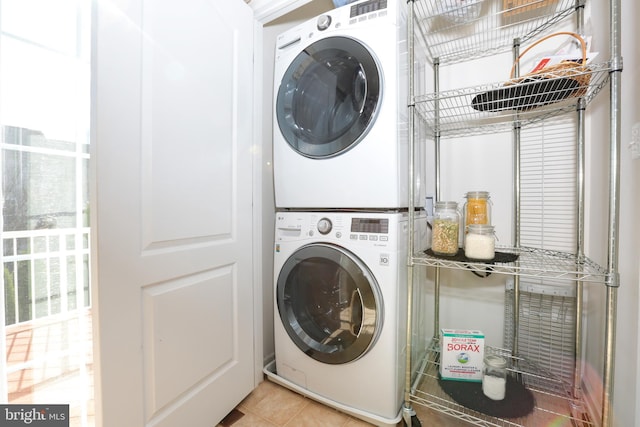 clothes washing area featuring light tile patterned floors and stacked washer and clothes dryer