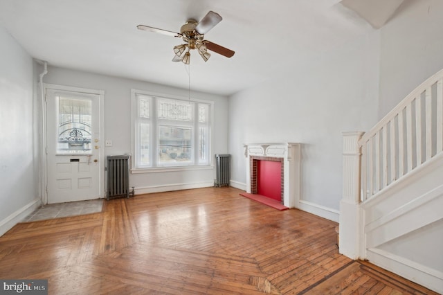 unfurnished living room with ceiling fan, parquet floors, and radiator