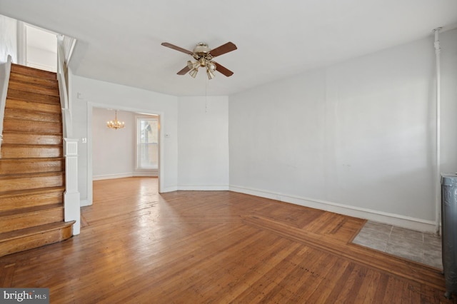 empty room featuring wood-type flooring and ceiling fan with notable chandelier