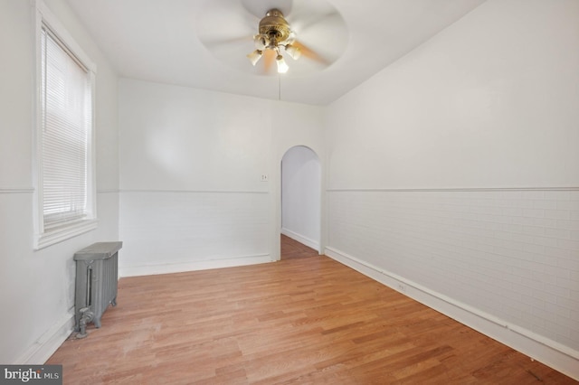 spare room featuring light wood-type flooring, radiator, and ceiling fan