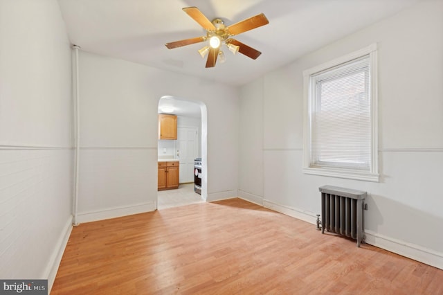 unfurnished room with ceiling fan, light wood-type flooring, and radiator