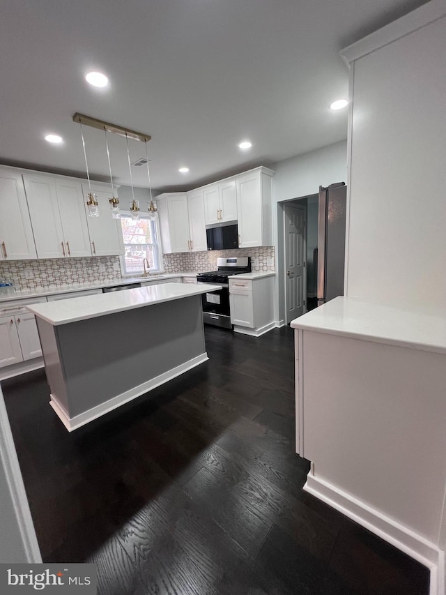 kitchen featuring decorative backsplash, appliances with stainless steel finishes, decorative light fixtures, dark hardwood / wood-style floors, and white cabinetry